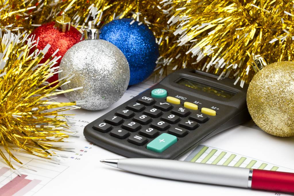 A calculator on top of tax documents, sitting next to some ornaments and tinsel.
