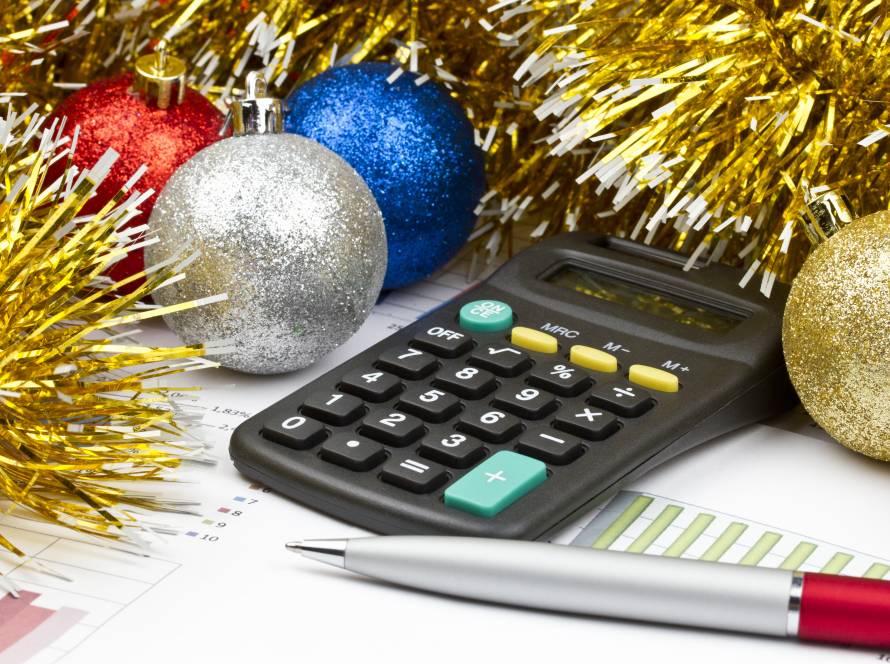 A calculator on top of tax documents, sitting next to some ornaments and tinsel.