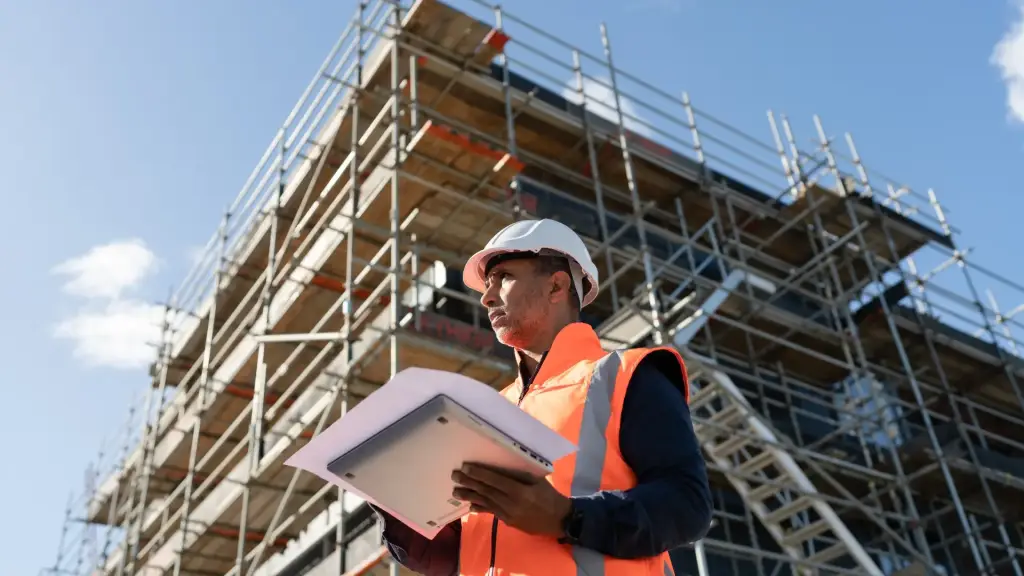 A contractor working at a construction site, reviewing paperwork.
