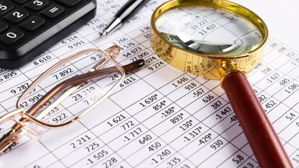 A tax document with glasses and a magnifying glass resting on top of it.