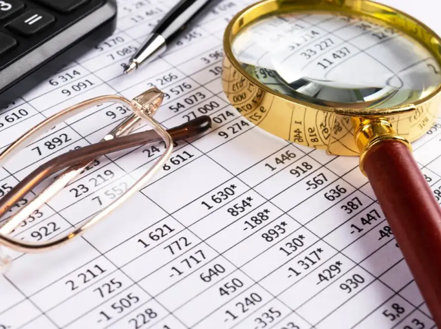 A tax document with glasses and a magnifying glass resting on top of it.