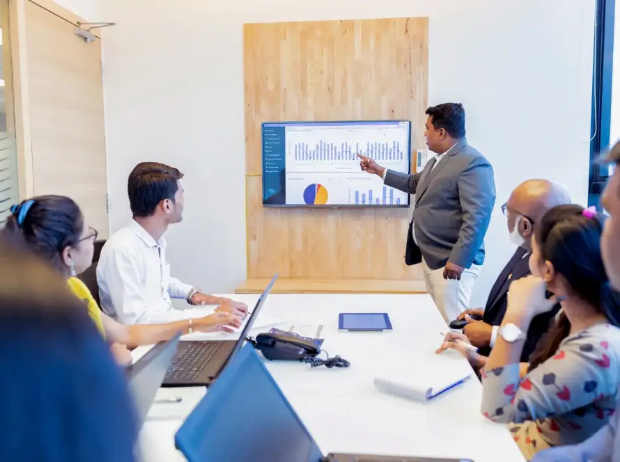 A financial advisor presenting business performance charts and graphs to a small business team in a conference room, representing outsourced CFO services and strategic financial planning.