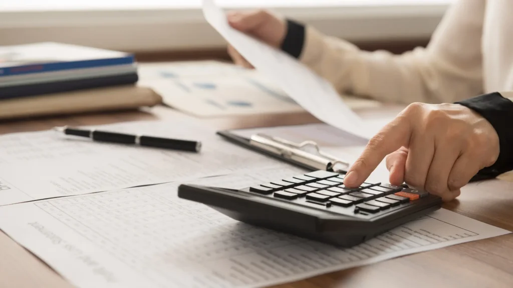 A small business owner reviews financial documents and accounting records at a desk, illustrating the choice between cash vs. accrual accounting methods.